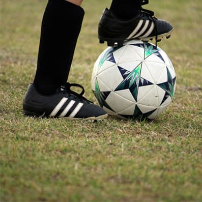 feet with cleats standing on a soccer ball